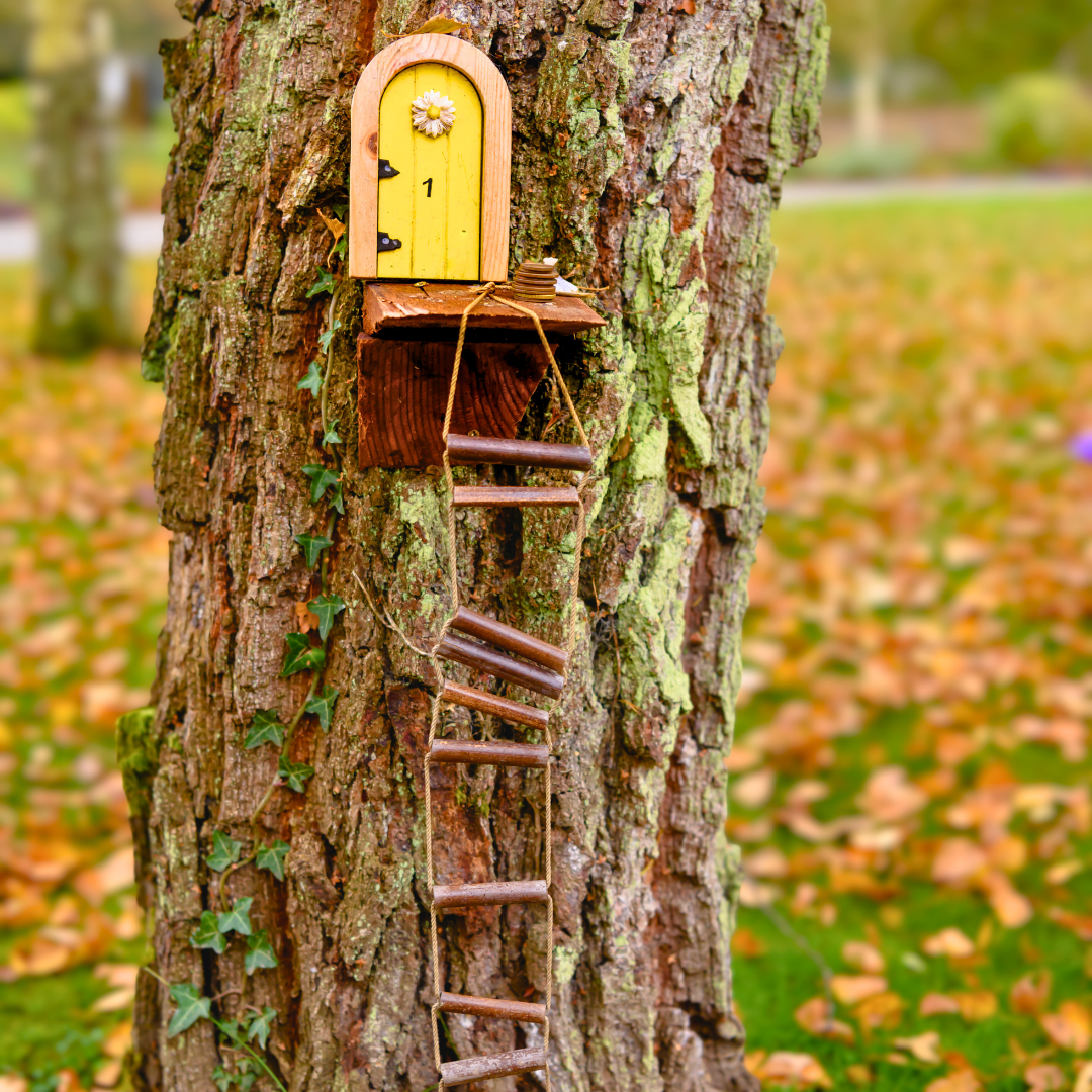 A fairy door with a ladder on a tree.